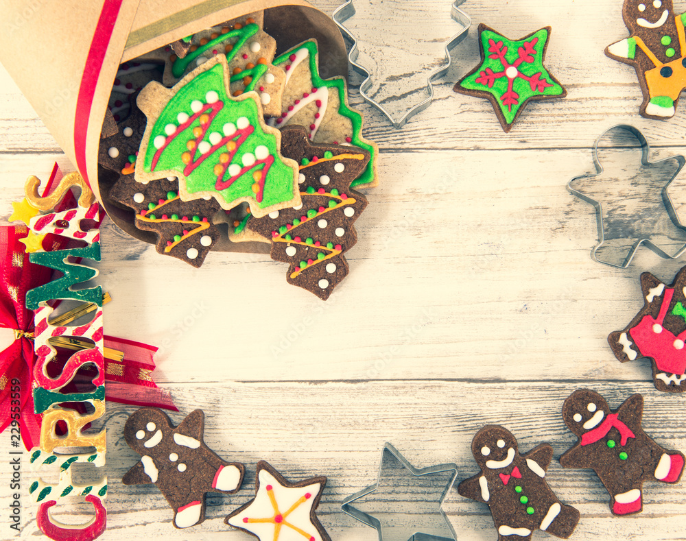 Obraz premium Beautiful Christmas composition and decoration with baked Christmas gingerbread cookies in paper bag on light wooden background, flat lay, top view, copy space (text space)