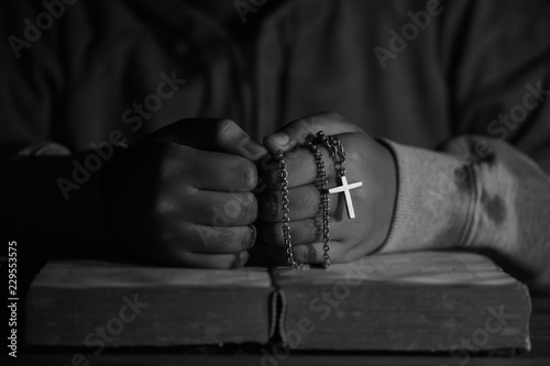 Teen girl praying on holy bible. Teenager woman hand with cross on Bible praying, Hands folded in prayer on a Holy Bible in church concept for faith, spirituality and religion. © doidam10