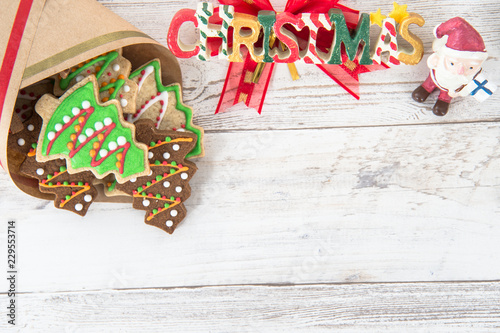 Beautiful Christmas composition and decoration with baked Christmas gingerbread cookies in paper bag on light wooden background, flat lay, top view, copy space (text space)