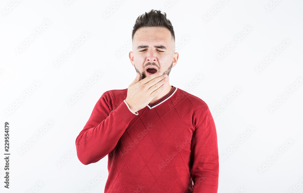 Close up portrait of young tired man yawning covering open mouth with hand Close up portrait of young tired man yawning covering open mouth with hand