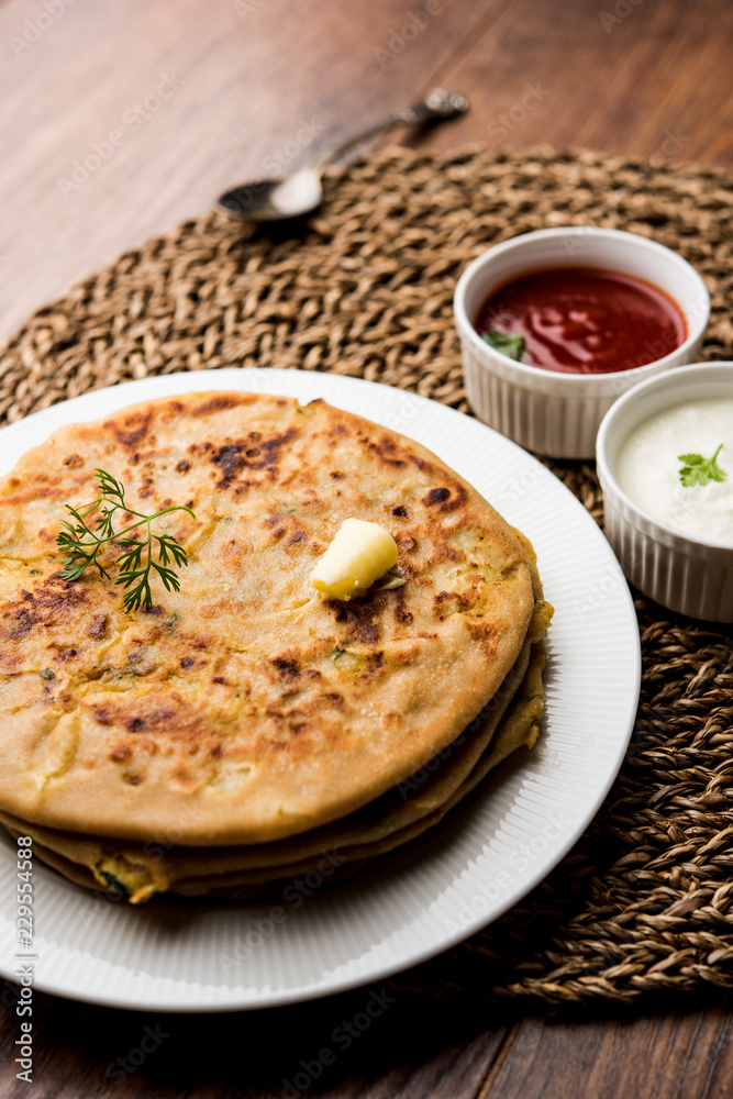 Aloo Paratha / Indian Potato stuffed Flatbread. Served with fresh curd and tomato ketchup. selective focus Aloo Paratha / Indian Potato stuffed Flatbread. Served with fresh curd and tomato ketchup. selective focus