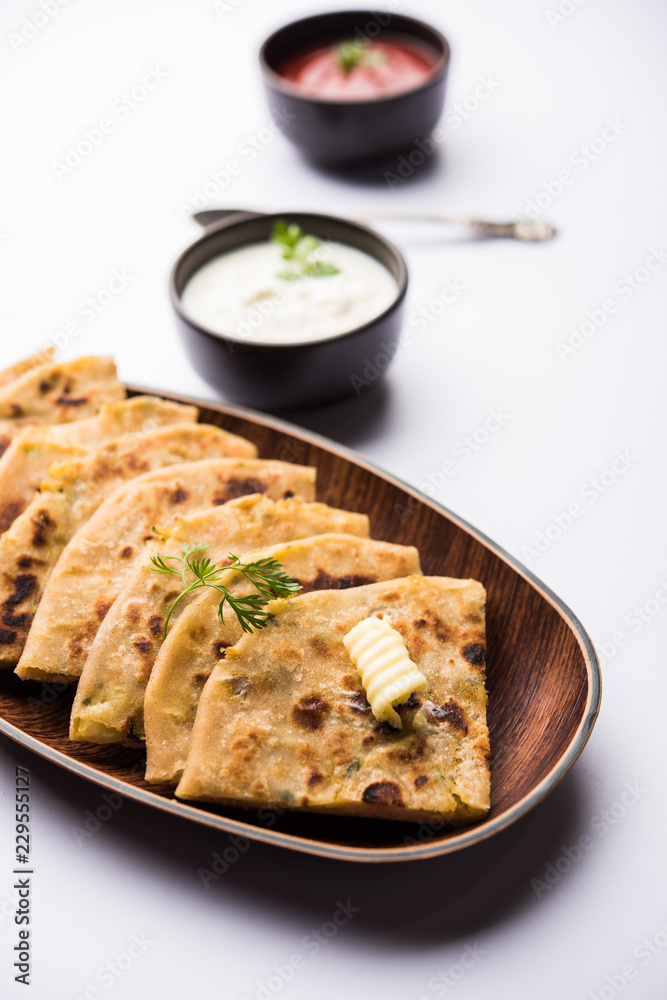 Aloo Paratha / Indian Potato stuffed Flatbread. Served with fresh curd and tomato ketchup. selective focus Aloo Paratha / Indian Potato stuffed Flatbread. Served with fresh curd and tomato ketchup. selective focus