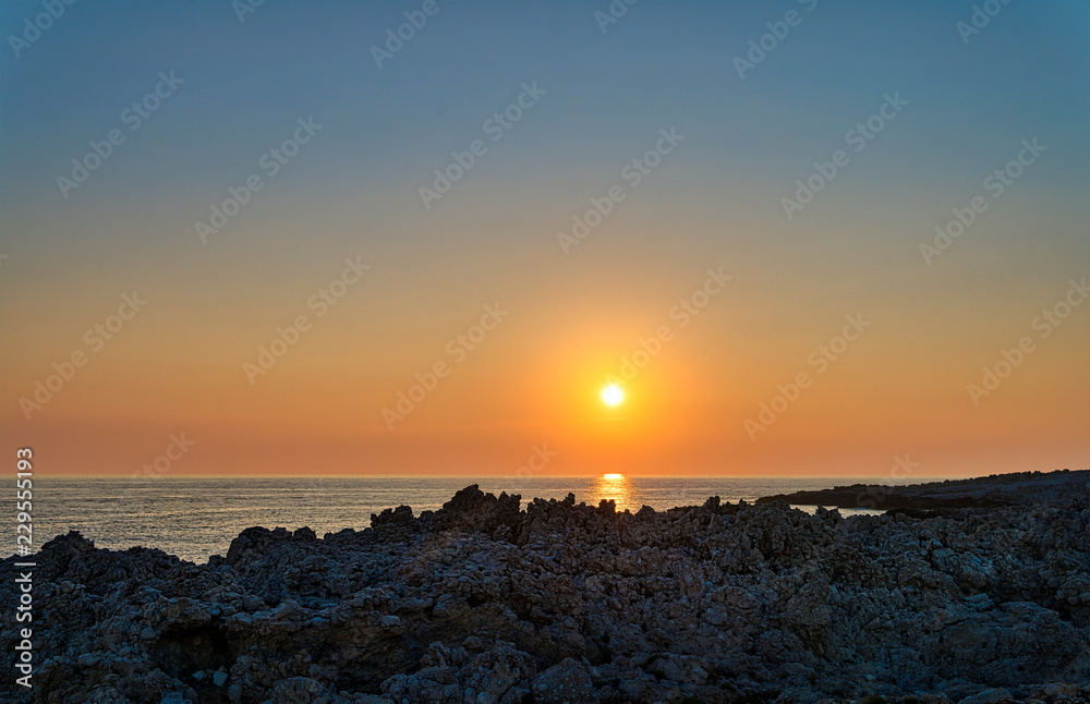 sunset over the sea with rough rocky shore