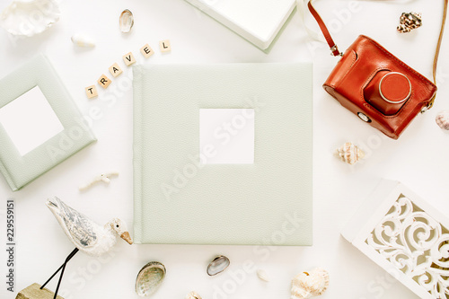 Travel styled composition with photo album, retro camera, bird sculpture on white background. Flat lay, top view traveler blog hero header.