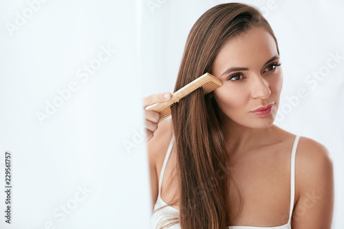 Hair Care. Woman Combing Beautiful Long Hair With Wooden Brush