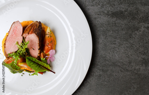 Duck fillet with figs and carrot puree on a white plate