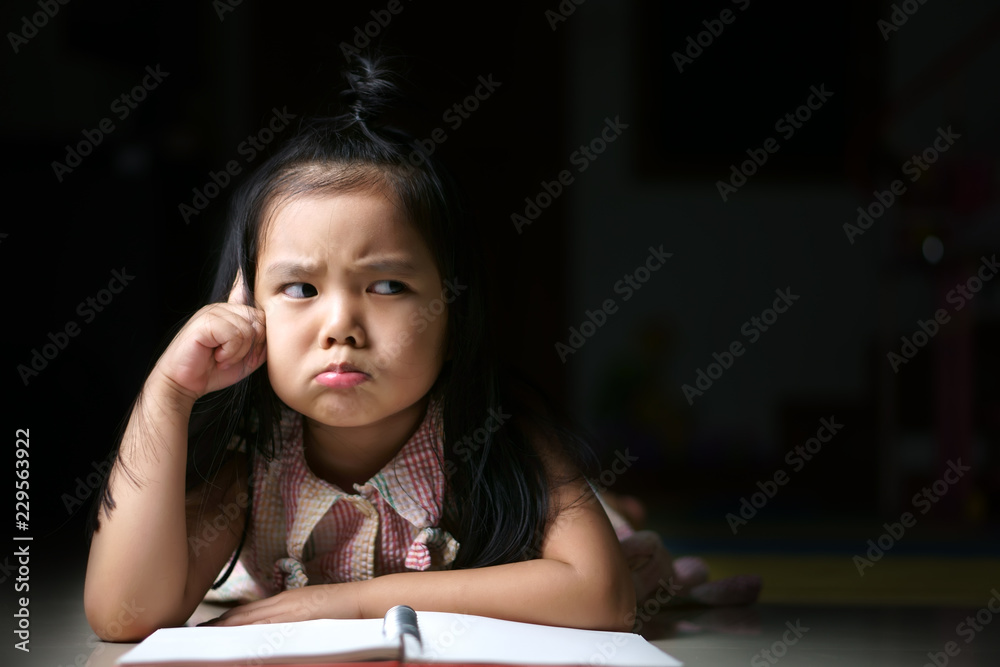 Asian child strain or kid girl student sleep reading and thinking for new idea on homework and diary or book on the floor at kindergarten classroom or nursery pre school and home with black space Asian child strain or kid girl student sleep reading and thinking for new idea on homework and diary or book on the floor at kindergarten classroom or nursery pre school and home with black space