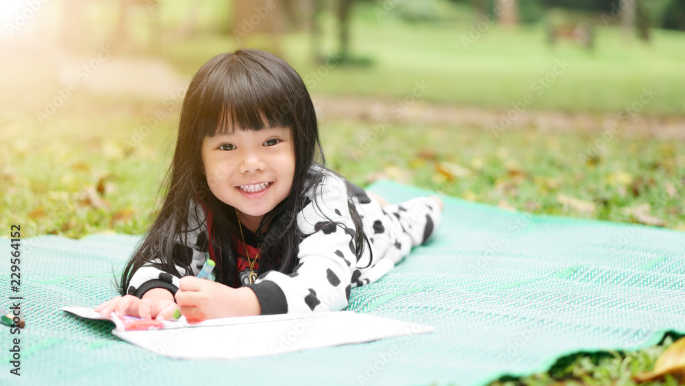 Asian child cute or kid girl learning for coloring or sleep drawing paint on green mat and nature meadow at autumn winter garden with happy smile white teeth and preschool education on holiday relax Asian child cute or kid girl learning for coloring or sleep drawing paint on green mat and nature meadow at autumn winter garden with happy smile white teeth and preschool education on holiday relax