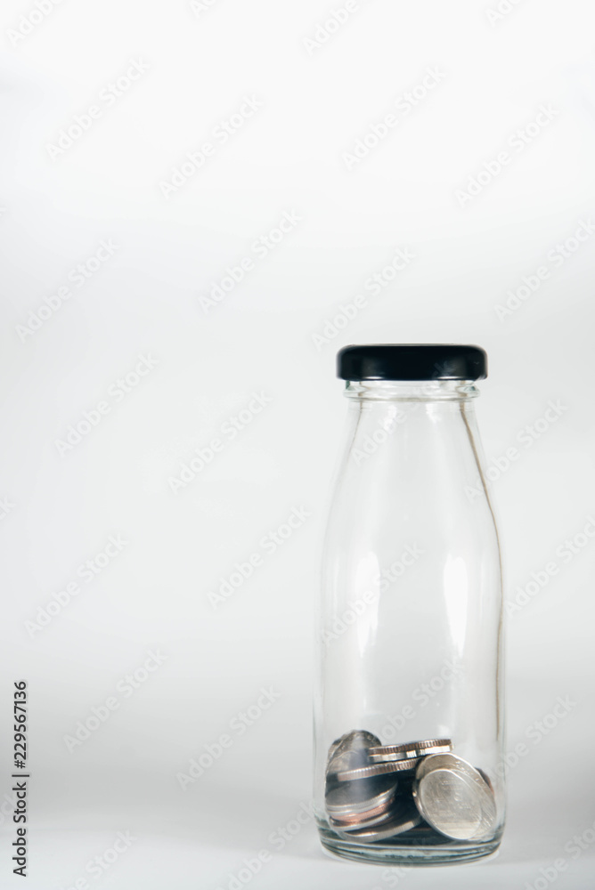 Coins in glass bottles on white background Coins in glass bottles on white background