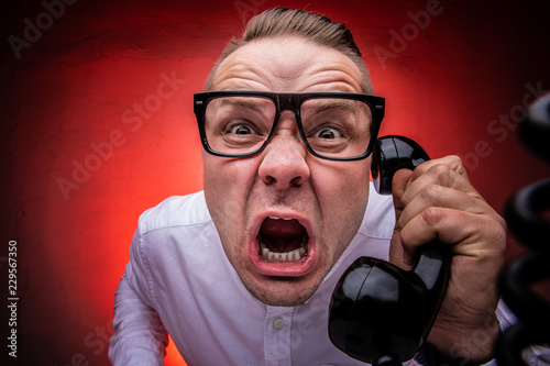 Hysterical and crazy boss screaming on the phone. Bad boss concept. Harassing phone calls. photo