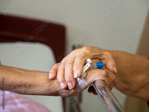 Wife visiting husband in hospital. Senior couple holding hands on hospital bed for hospitalization for supporting his dear. Concept of love and to be with lover.