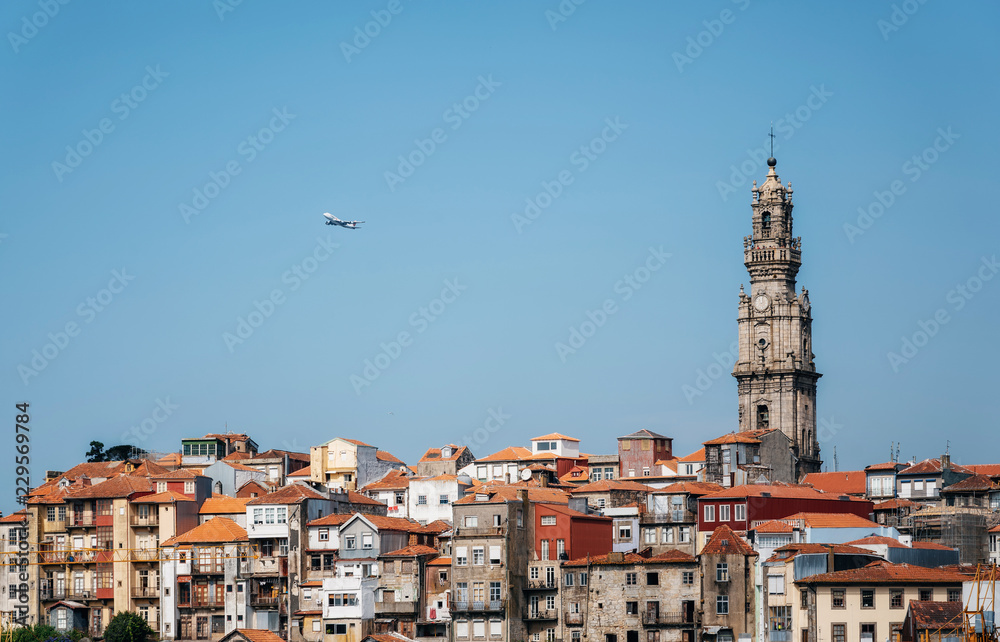Porto cityscape with Clerigos tower and airplane in blue sky, Portugal