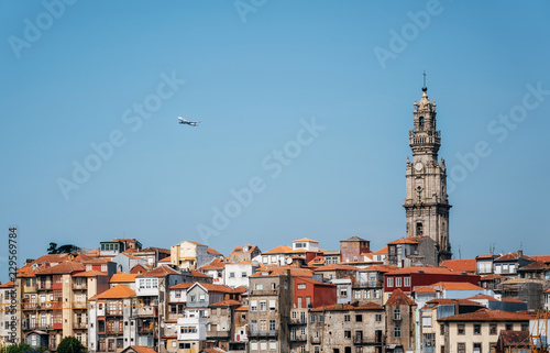 Porto cityscape with Clerigos tower and airplane in blue sky, Portugal © bortnikau