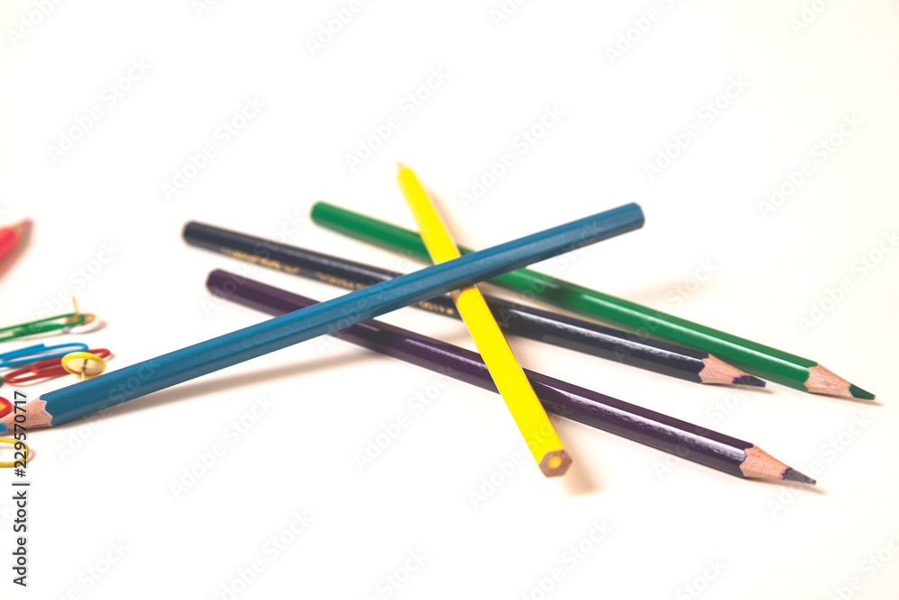colorful pencils with paperclips on white desk colorful pencils with paperclips on white desk
