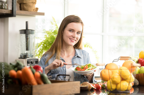 Healthy young woman eating salad in the kitchen