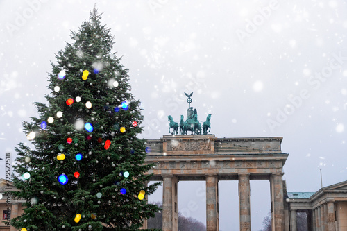 Bradenburg Gate with decorated Christmas tree at winter day with falling snow, Berlin, Germany