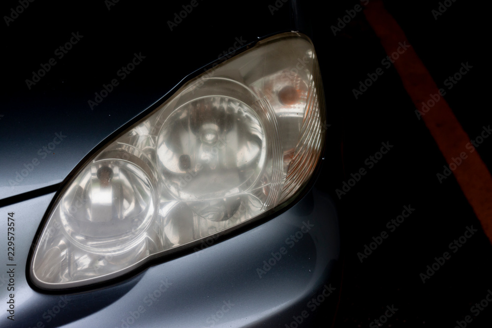The headlights of car are cloudy with dark tone in parking area.
