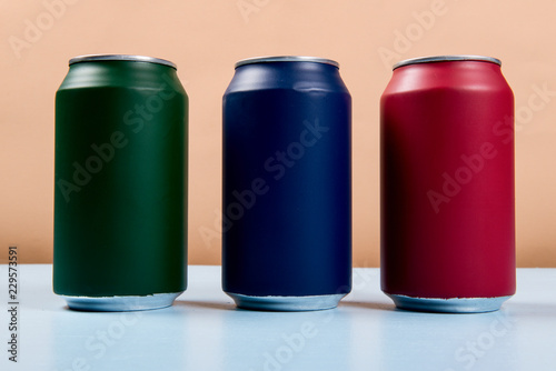 three colored cans of soft drinks closed on a light blue background
