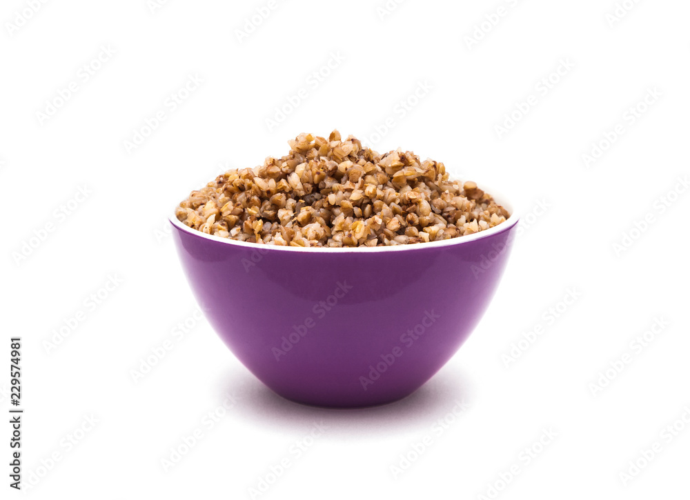 Dry buckwheat in purple ceramic bowl isolated on white Dry buckwheat in purple ceramic bowl isolated on white