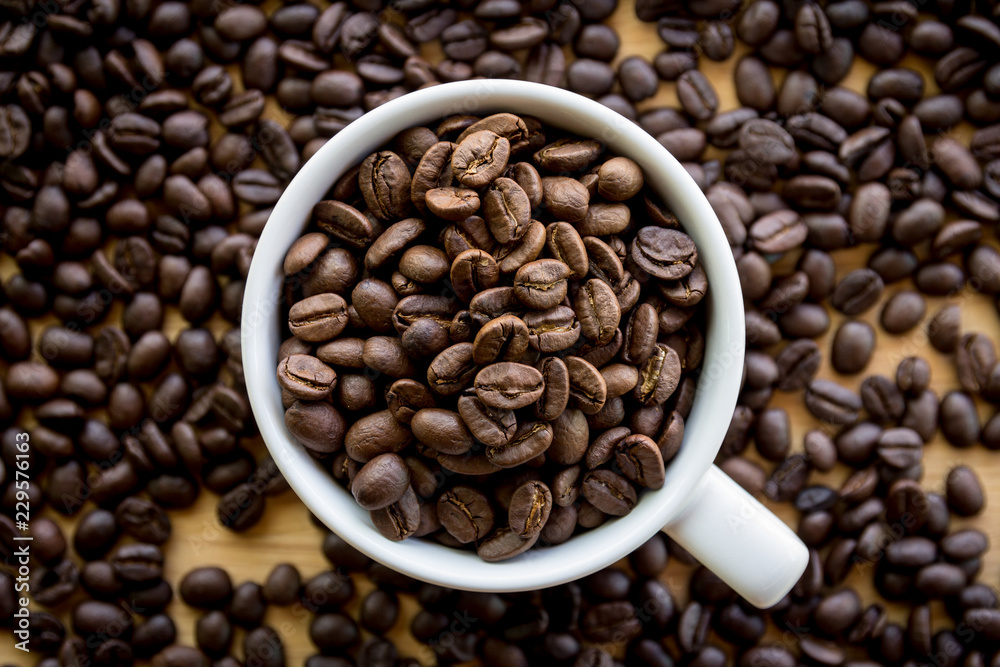 Close up of white coffee cup full of coffee beans background with copy space Close up of white coffee cup full of coffee beans background with copy space