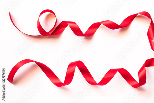 Red satin ribbon curly bow color isolated on white background with clipping path for Christmas holiday greeting card design decoration element