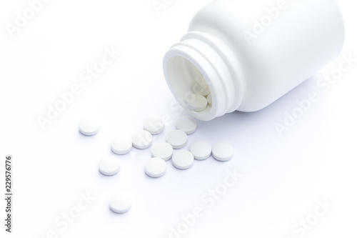 Close up of teblets pills an pill bottle on white background with selective focus