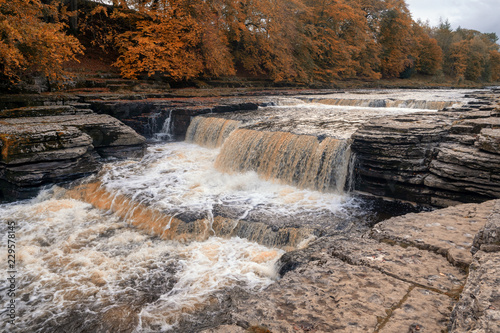 Aysgarth Falls are a triple flight of waterfalls  surrounded by forest carved out by the River Ure over an almost one-mile stretch on its descent to mid-Wensleydale in the Yorkshire Dales