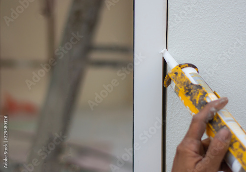 Repairman’s hand installing the windows with gun silicone. closeup