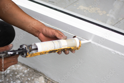 Repairman’s hand installing the windows with gun silicone. closeup photo