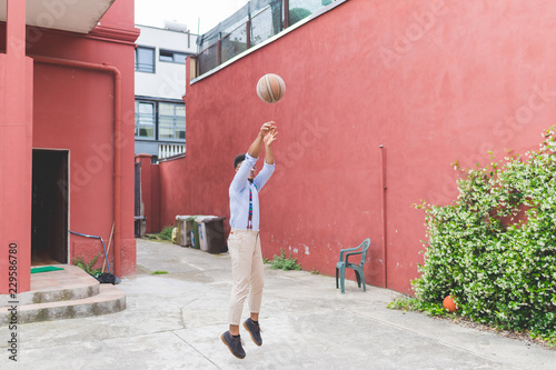 Man throwing basketball mid air on street photo