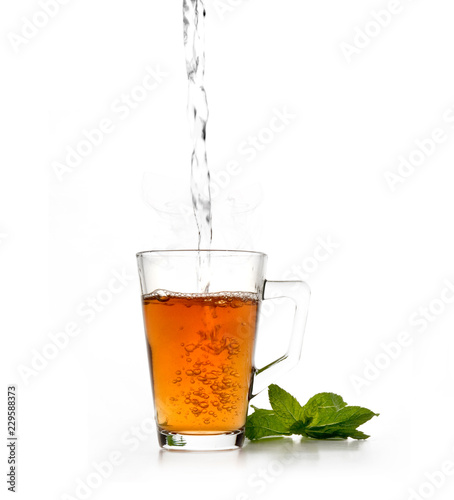 фотографія Corrro de agua cayendo en un vaso de cristal con té y menta