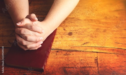 Woman Praying with Her Hands Folded over Her Bible