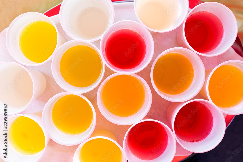 Mix of children drinks in white plastic cups from above. Mix of children drinks in white plastic cups from above.