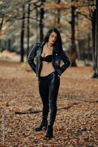 Beautiful dark haired young woman wearing a black bra, leather jacket and  black leather pants posing in the woods on a sunny autumn afternoon. Stock  Photo | Adobe Stock