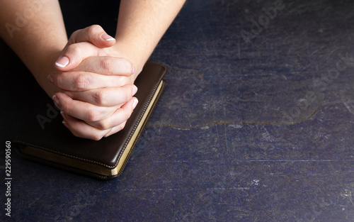 Woman Praying with Her Hands Clasped on a Bible photo