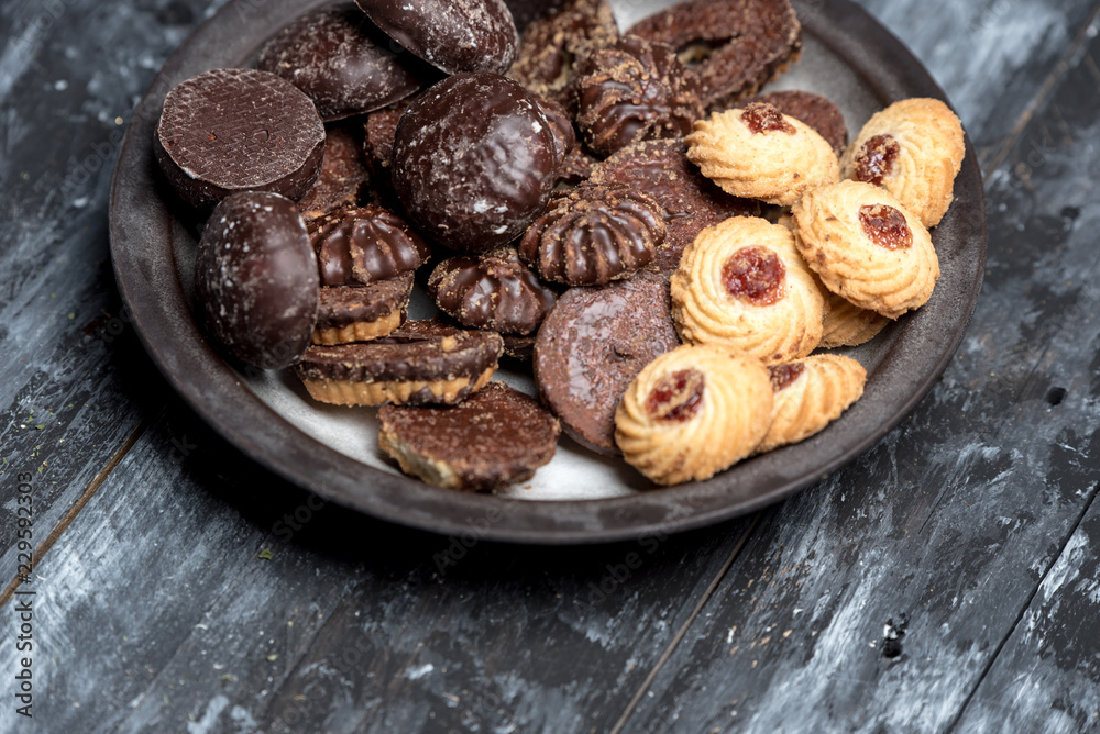 shortbread butter cookies with chocolate and plum jam on dark wooden table
