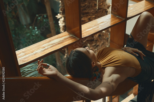 Preety Woman Relaxing while lying on a wooden stair railing near
