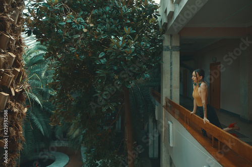 Pretty young woman standing in hotel balcony, looking out enjoyi photo