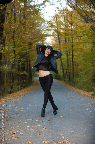 Young woman posing a an autumn day on a road in the woods. © xpabli