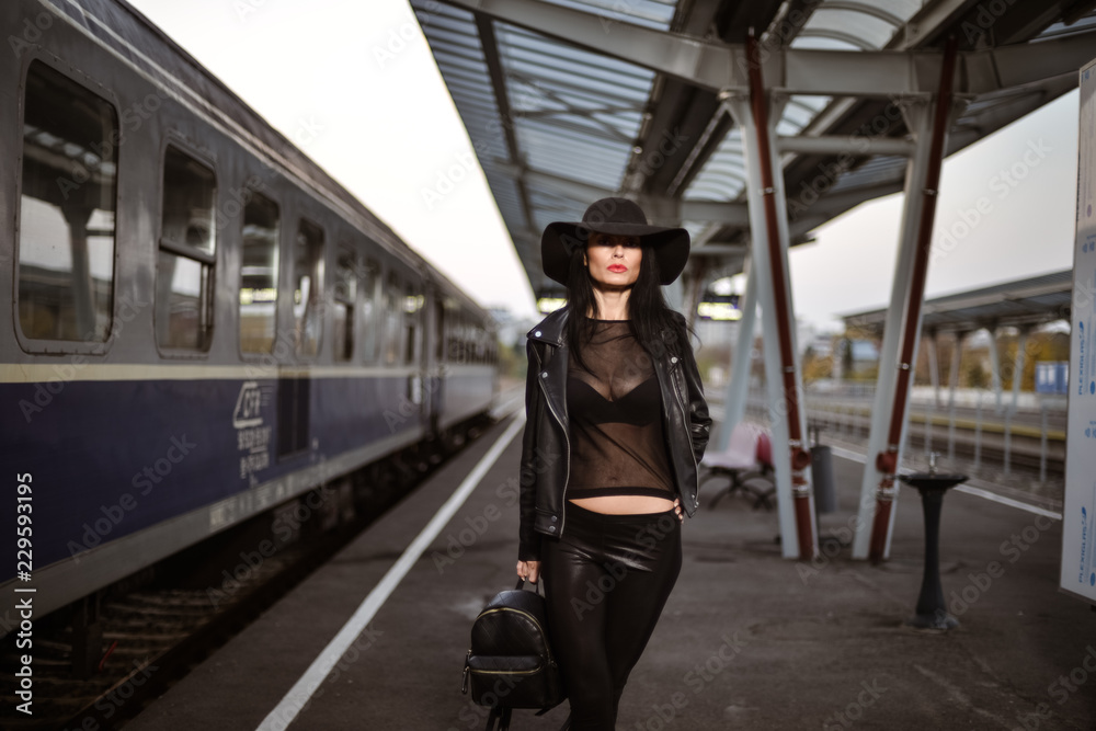 Young sexy woman dressed in black posing on a train station pier. Young sexy woman dressed in black posing on a train station pier.
