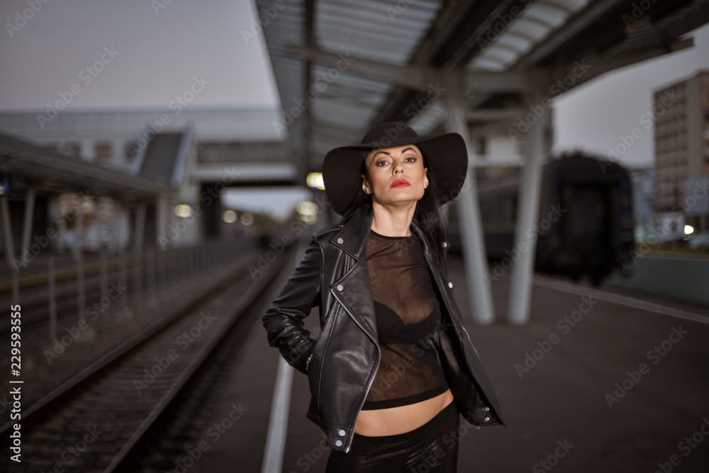 Young sexy woman dressed in black posing on a train station pier. Young sexy woman dressed in black posing on a train station pier.