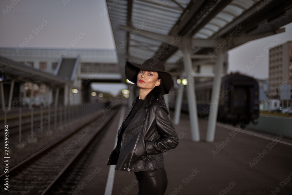 Young sexy woman dressed in black posing on a train station pier. Young sexy woman dressed in black posing on a train station pier.