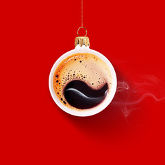 Christmas toy is made from a fragrant cup of coffee. Christmas toy. Holiday concept. Fragrant coffee on a red background for your advertising. Smoke from hot coffee.