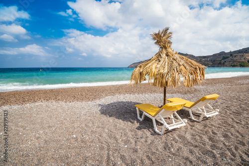 Fototapeta Naklejka Na Ścianę i Meble -  Empty sunbeds and umbrella on Vlycha beach near Lindos village (Rhodes, Greece)