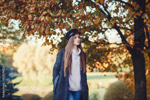 Beautiful happy girl with long hair, wearing stylish hat, coat posing in autumn park. Outdoor portrait, day light.