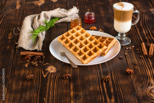 fresh belgian waffles, tasty jam and latte coffee on a wooden background. top view.