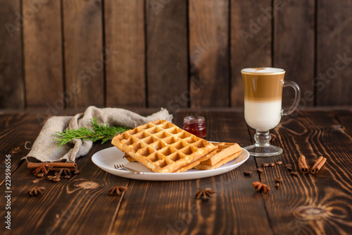 fresh belgian waffles, tasty jam and latte coffee on a wooden background. top view. photo