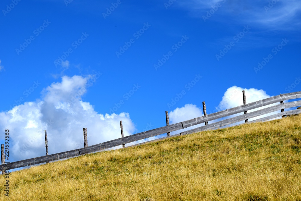 Holzzaun auf einer Weide in den Südtiroler Bergen, freigestellt vor blauen Himmel Holzzaun auf einer Weide in den Südtiroler Bergen, freigestellt vor blauen Himmel