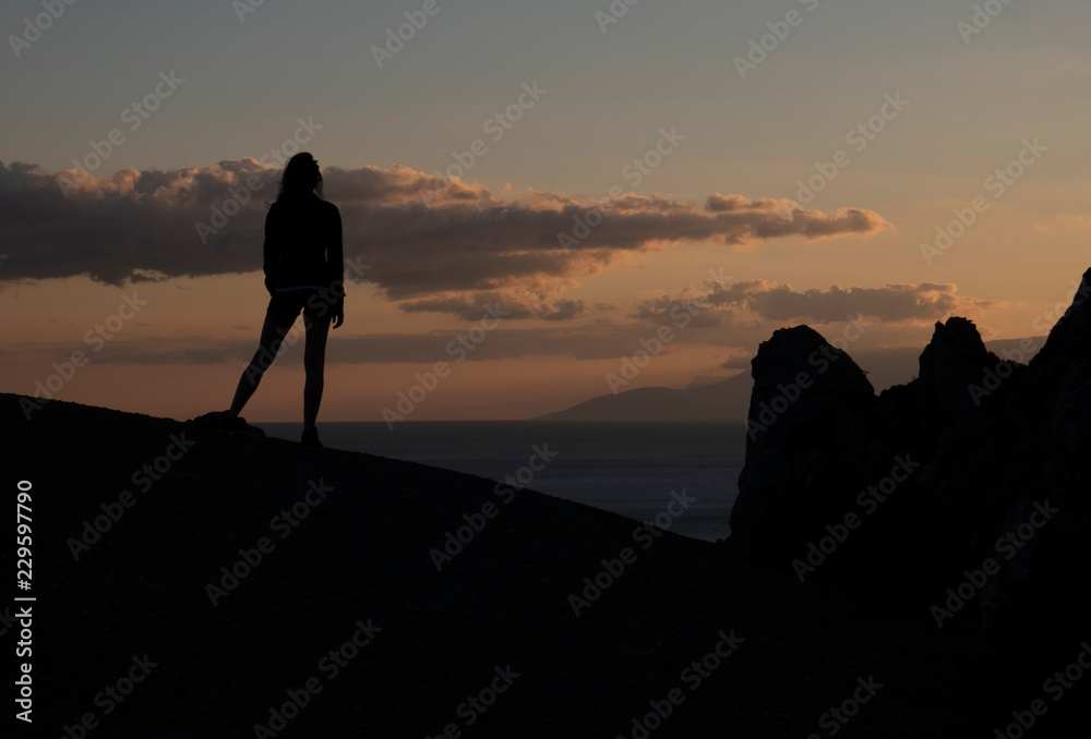 Silhouette of woman in the mountains on top at sunset at dawn