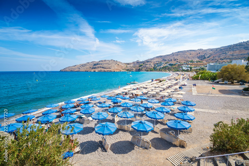 Sunbeds and umbrellas on Vlycha beach near hotel resort (Rhodes, Greece)